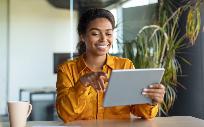 Modern technologies in business. Happy black businesswoman using modern digital tablet, working